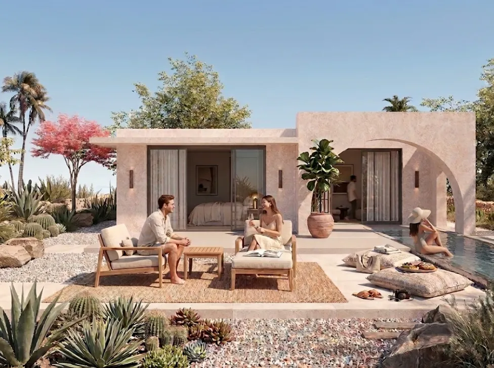 A warm, adobe-style villa with a shaded terrace, desert plants and morning light
